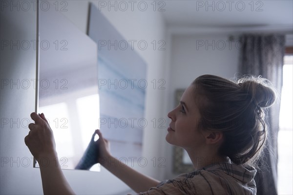 Woman hanging painting on wall