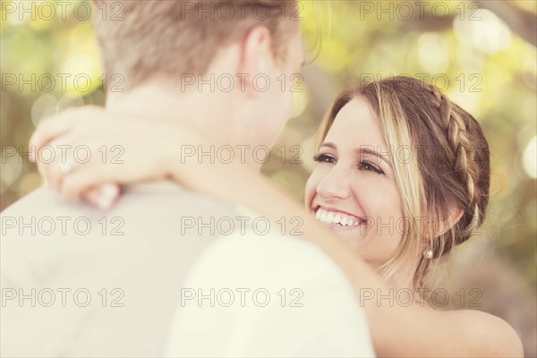 Caucasian bride and groom hugging outdoors