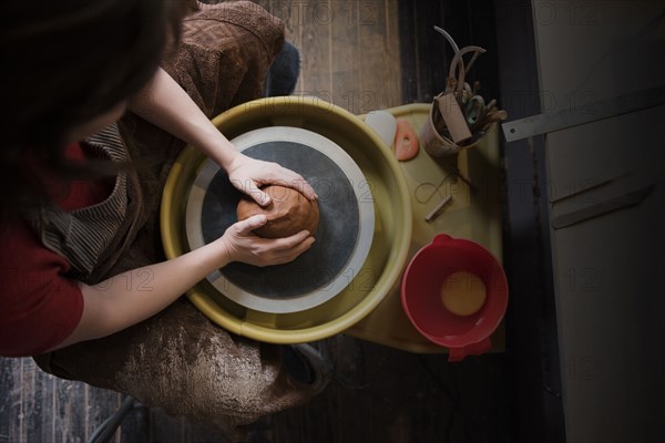 Caucasian woman shaping pottery clay on wheel