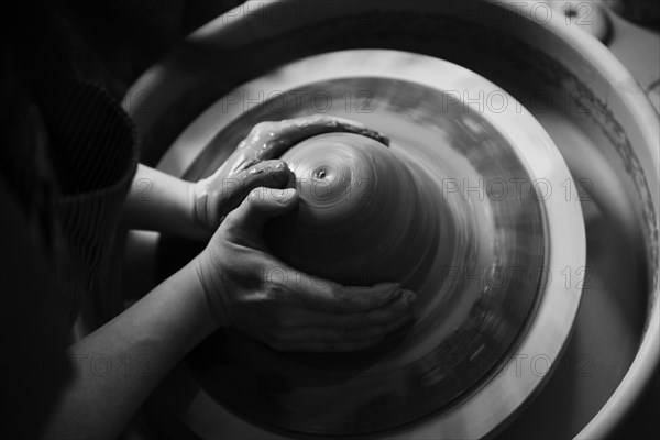Hands of Caucasian woman shaping pottery clay on wheel