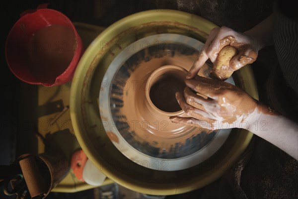 Hands of Caucasian woman shaping pottery clay on wheel