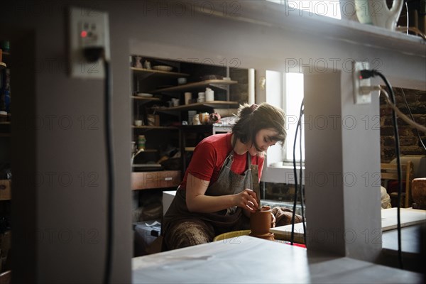 Caucasian woman shaping pottery clay on wheel