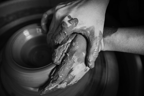 Hands of Caucasian woman shaping pottery clay on wheel