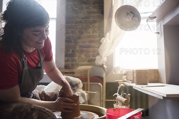 Caucasian woman shaping pottery clay on wheel