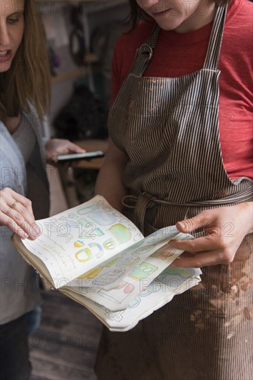 Caucasian women examining drawings in book