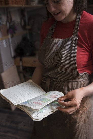 Caucasian woman examining drawings in book