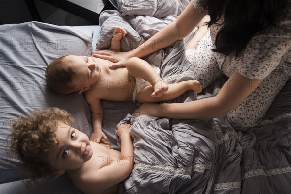 Caucasian mother playing with sons in bed