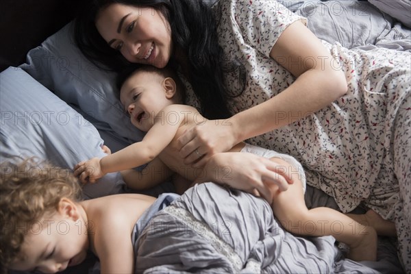 Caucasian mother playing with sons in bed