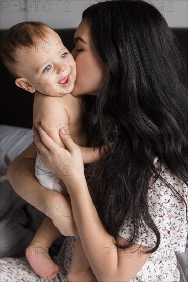 Caucasian mother kissing baby son in bed