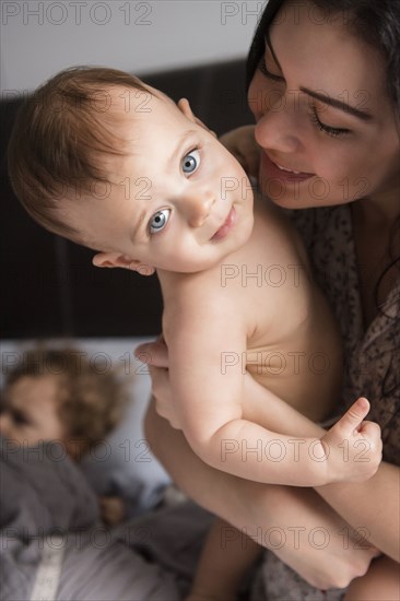 Caucasian mother holding baby son in bed