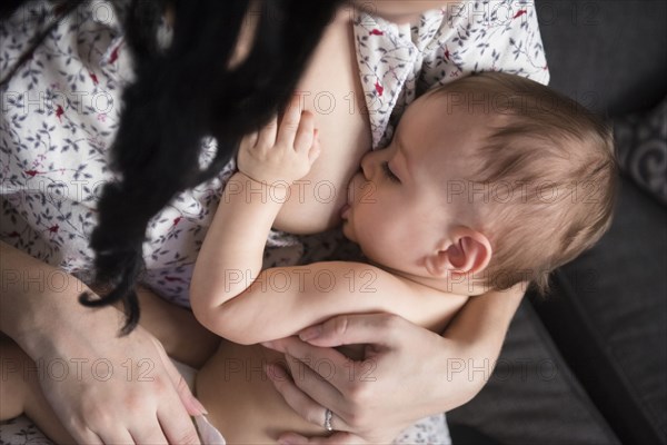 Caucasian mother breastfeeding baby son on sofa