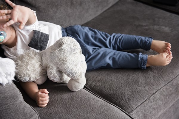 Caucasian boy laying on sofa gesturing stop