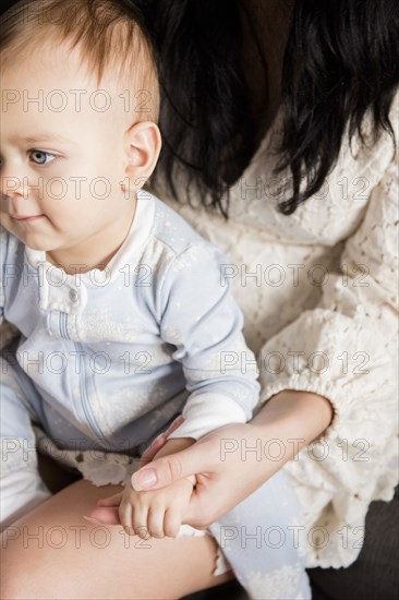 Caucasian baby boy sitting in lap of mother