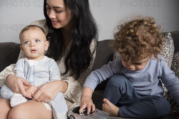 Caucasian mother sitting on sofa with sons