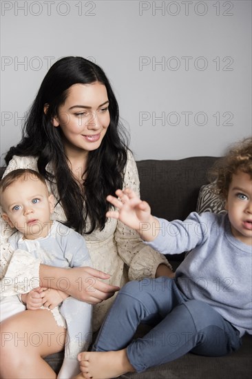 Caucasian mother sitting on sofa with sons