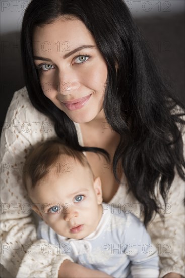 Caucasian mother sitting on sofa with baby son in lap