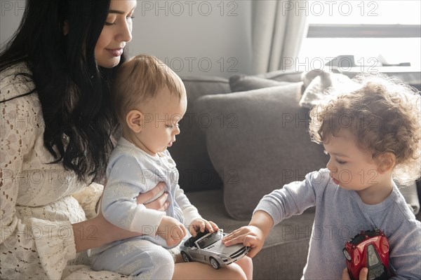 Caucasian mother watching sons playing with toy cars