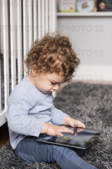 Caucasian boy sitting on floor playing with digital tablet