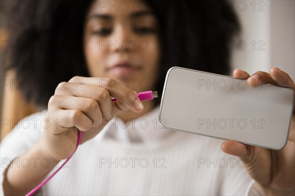 African American woman connecting cable to cell phone