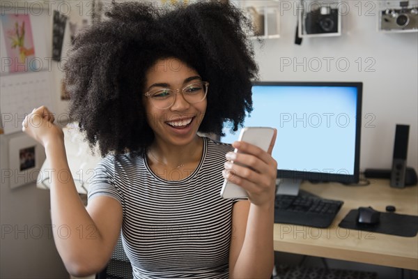 African American woman texting on cell phone and celebrating