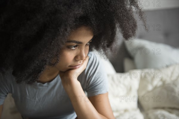 Unhappy African American woman sitting in bed