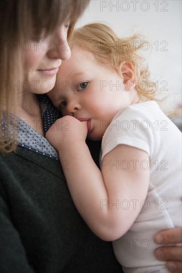 Caucasian mother holding daughter sucking thumb