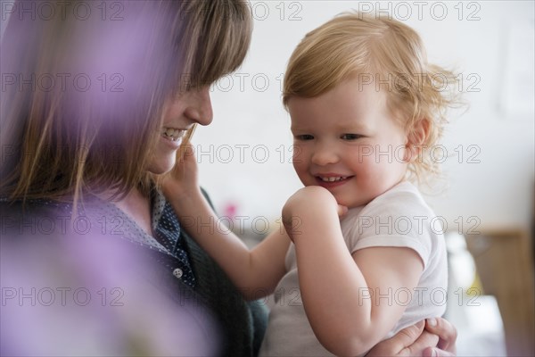 Caucasian mother holding laughing daughter