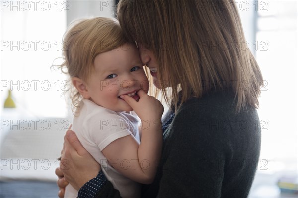 Caucasian mother holding smiling daughter