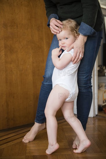 Caucasian mother and daughter tiptoeing barefoot