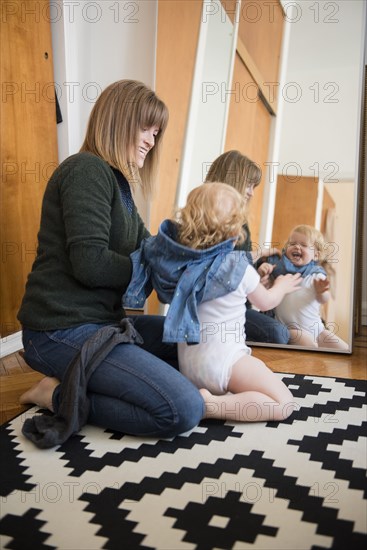 Reflection in mirror of Caucasian mother and daughter kneeling on floor