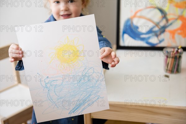 Caucasian girl showing drawing on paper