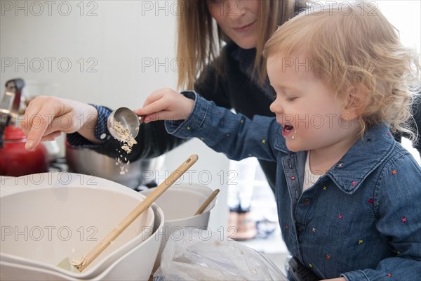 Caucasian girl cooking with mother in kitchen