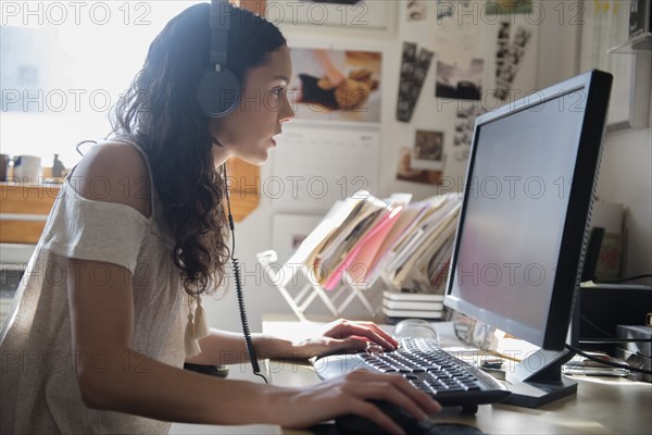 Hispanic woman listening to computer with headphones