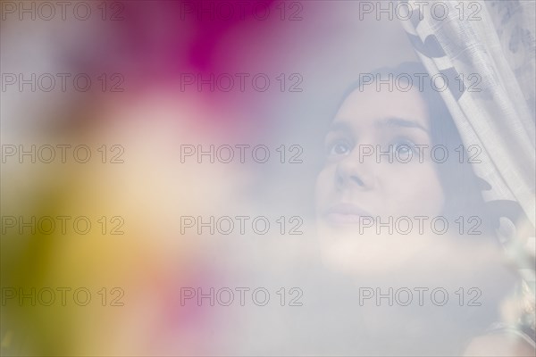 Hispanic woman opening curtain behind window