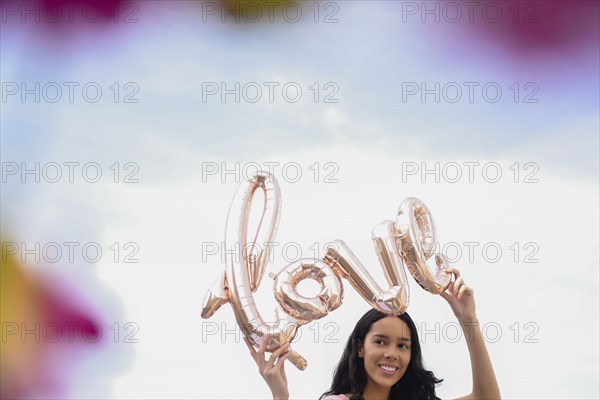 Hispanic woman holding love balloon outdoors