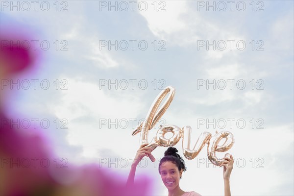 Hispanic woman holding love balloon outdoors