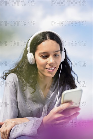 Hispanic woman listening to cell phone with headphones