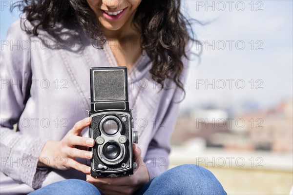 Hispanic woman using vintage camera