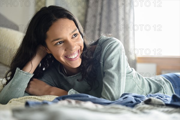 Smiling Hispanic woman laying on bed