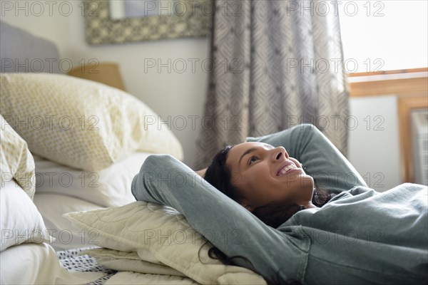 Smiling Hispanic woman laying on bed