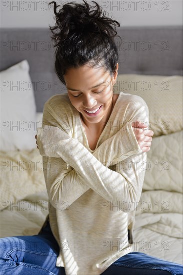 Cold Hispanic woman sitting on bed