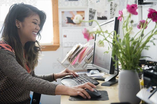 Mixed Race woman sitting at desk using computer