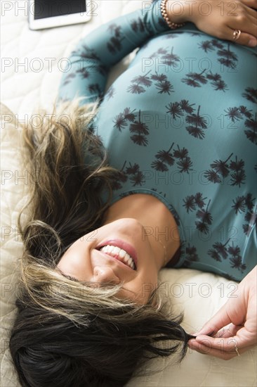 Mixed Race woman laying on bed pulling hair over eyes