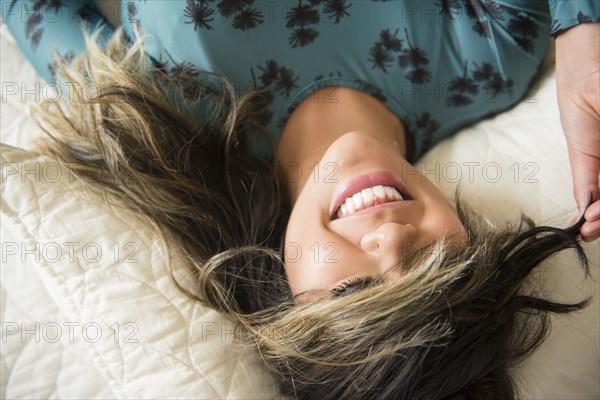 Mixed Race woman laying on bed pulling hair over eyes