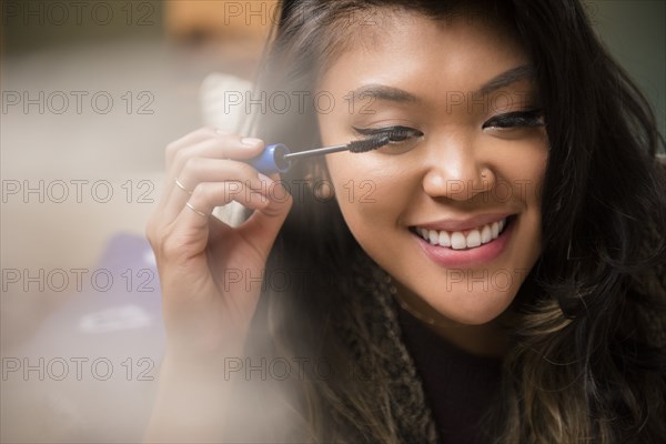 Mixed Race woman applying mascara