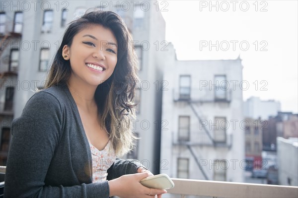 Mixed Race woman holding cell phone in city