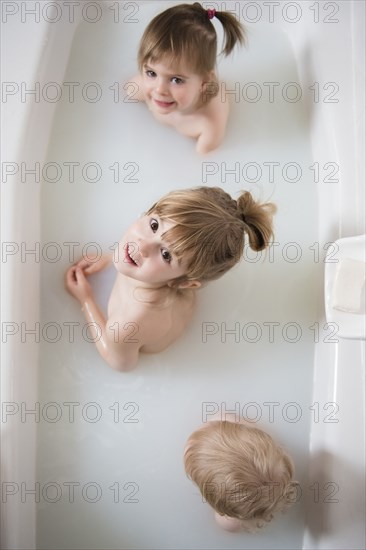 Caucasian boy and girls looking up in bathtub