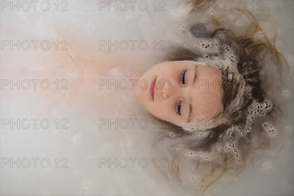 Face of Caucasian girl floating in bubble bath