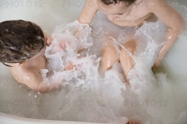 Caucasian girls splashing in bathtub