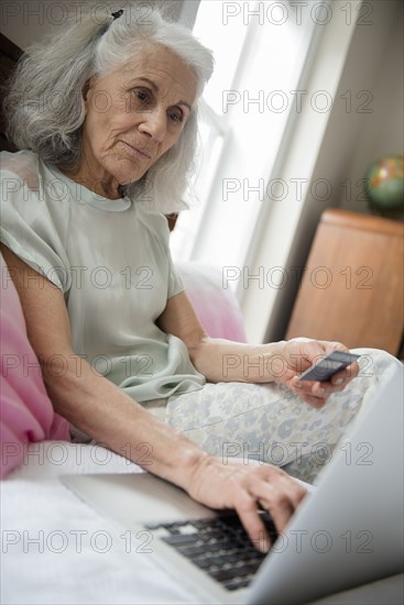 Older woman shopping online with credit card and laptop